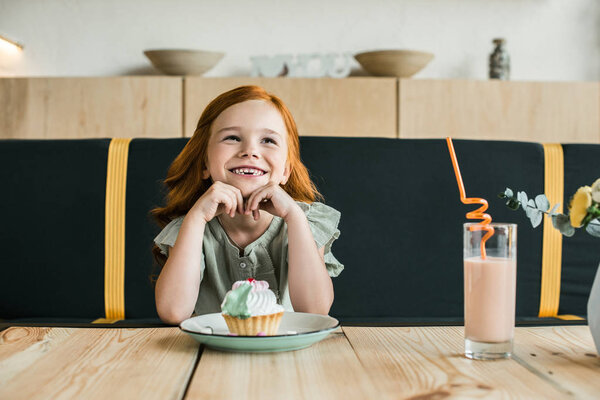 smiling girl with cupcake in cafe