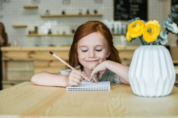 girl drawing at table in cafe 