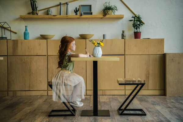 Κορίτσι σχεδίασης στο τραπέζι στην καφετέρια — Φωτογραφία Αρχείου