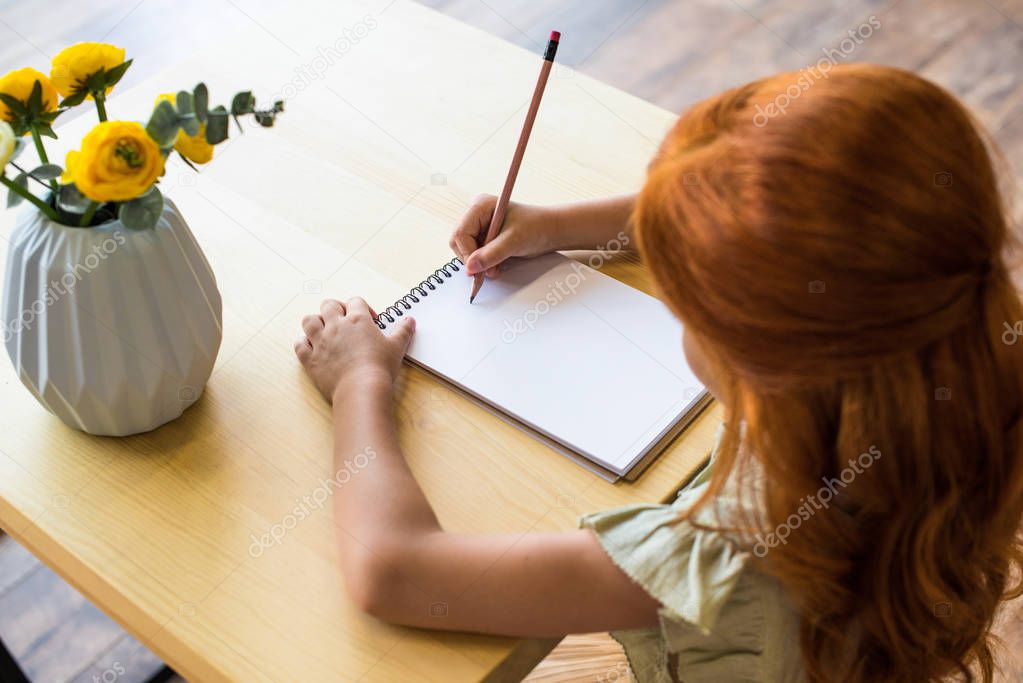 redhead girl drawing at table 