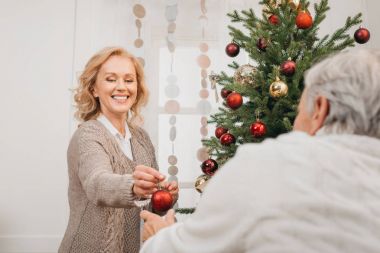 Erkek ve kadın Noel ağacı süslüyorlar.