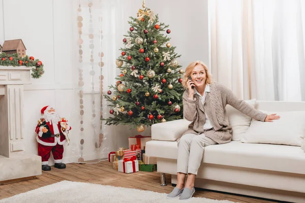 Женщина разговаривает на смартфоне возле рождественской елки — стоковое фото