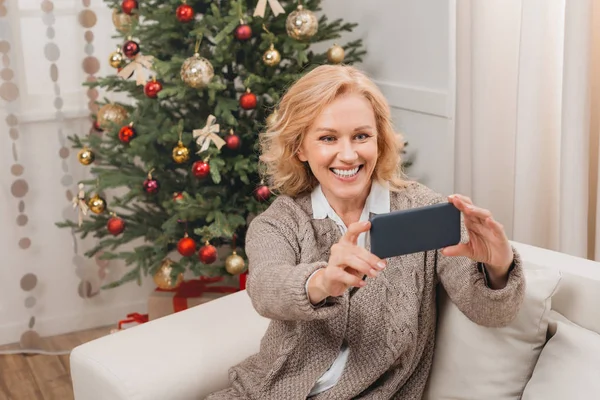 Woman taking selfie with christmas tree — Stock fotografie