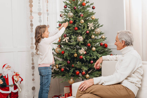 grandfather and granddaughter decorating christmas tree
