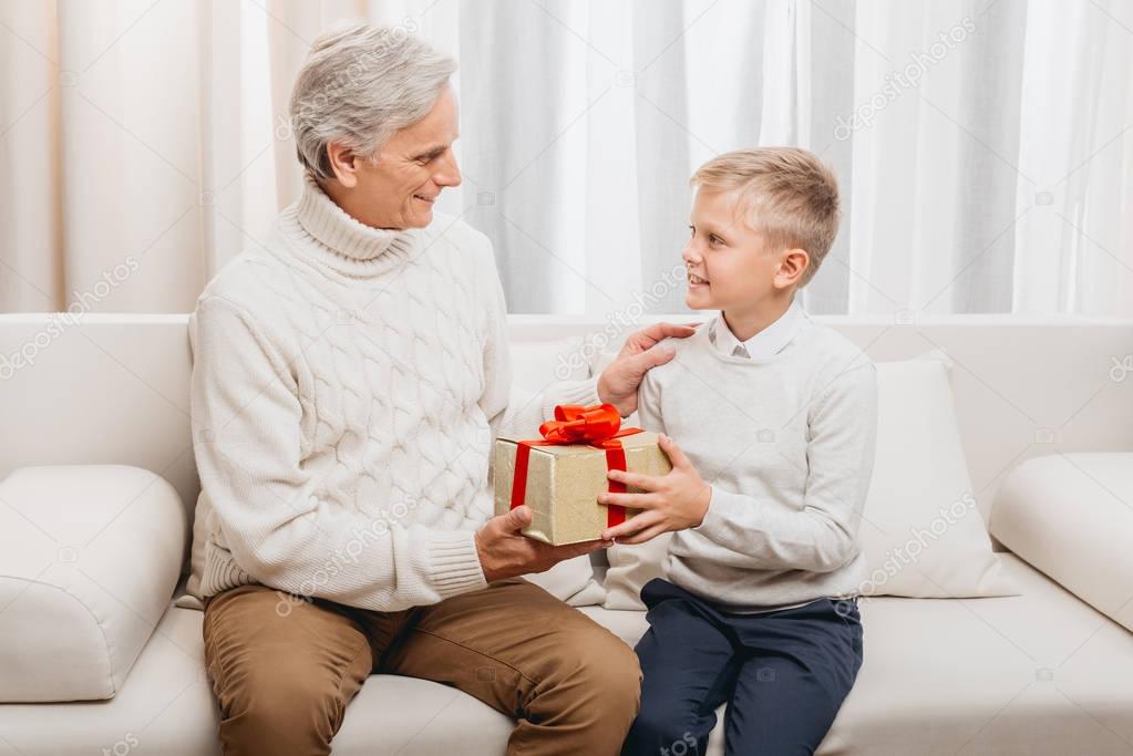 grandfather presenting christmas gift to grandson