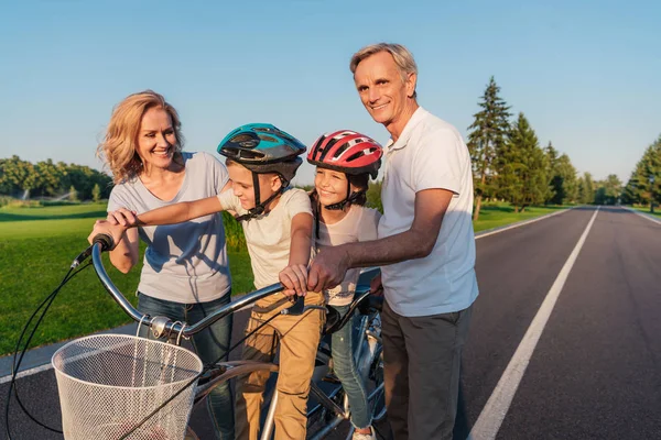 Grandparents helping children ride bicycle — Stock Photo, Image