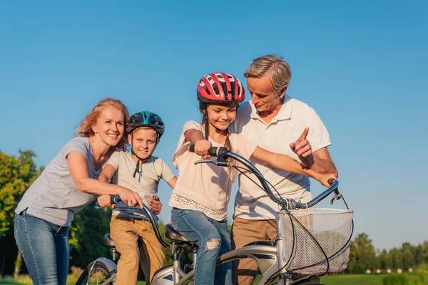 Abuelos ayudando a los niños a montar en bicicleta — Foto de Stock