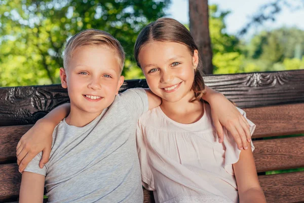 Barnen sitter på bänken i parken — Stockfoto