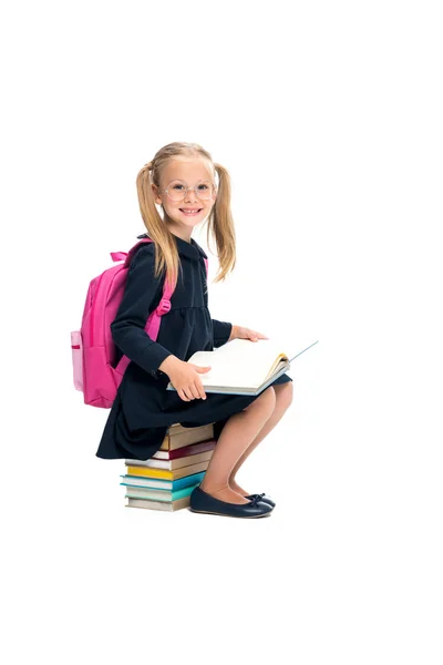 Schoolmeisje zittend op stapel boeken — Stockfoto