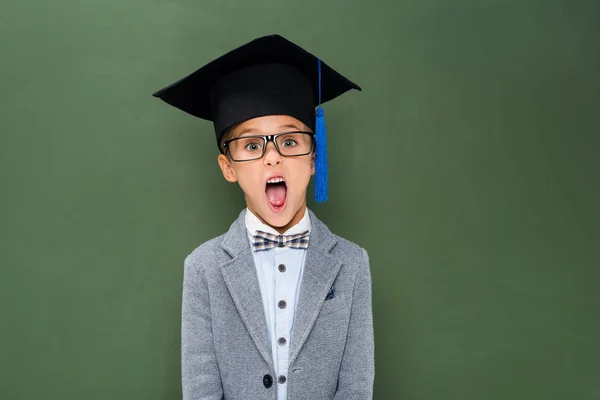 Shocked schoolboy in graduation hat — Stock Photo, Image