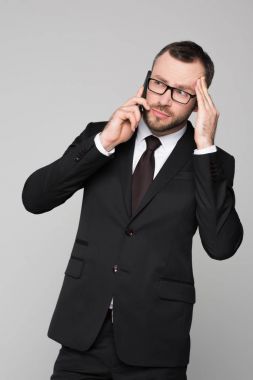 Young businessman on phone touching his temple clipart