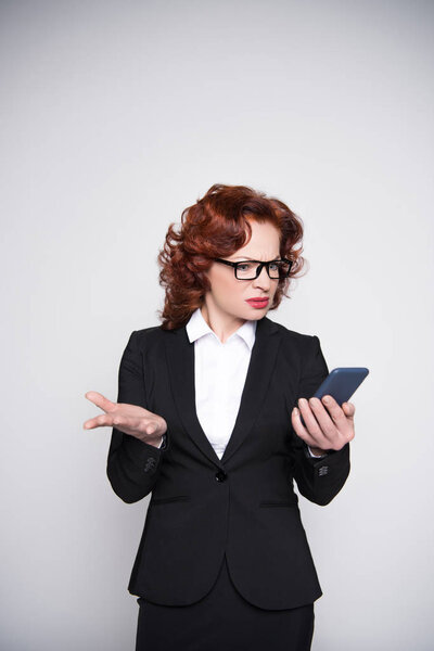 confused businesswoman looking at smartphone