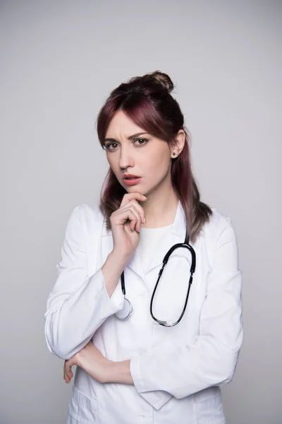 Молода жінка-лікар торкається підборіддя — стокове фото