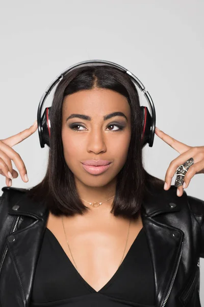 Smiling young woman touching headphones — Stock Photo, Image