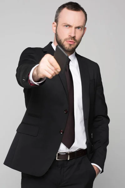 Young businessman holding out smartphone — Stock Photo, Image