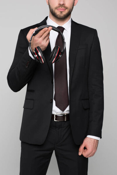 Young businessman holding headphones in hands