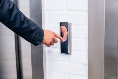Asansör düğmesine basarak takım elbiseli adam