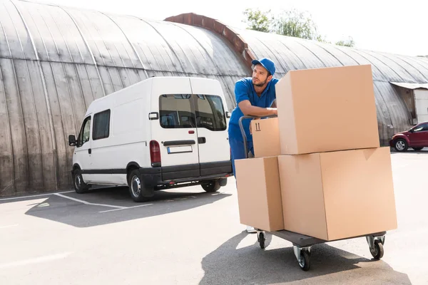 Leveringsman met dozen op winkelwagen — Stockfoto