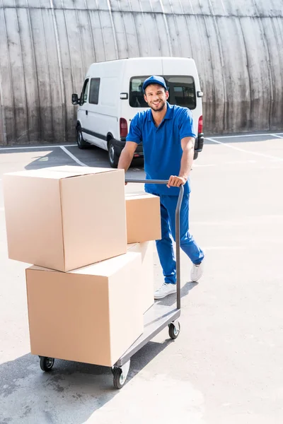 Leveringsman met dozen op winkelwagen — Stockfoto