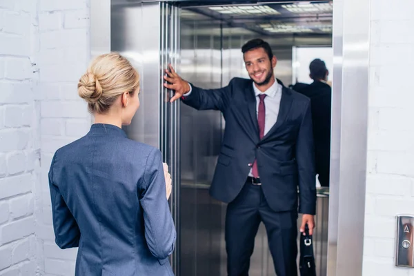 Uomo d'affari in possesso di ascensore porta per donna — Foto Stock
