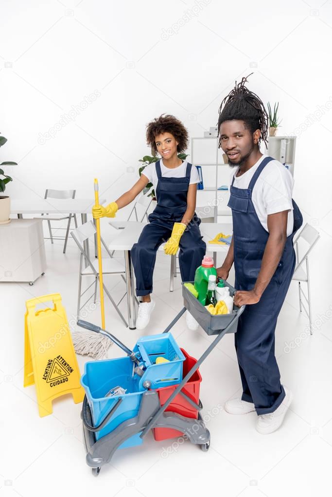 african american cleaners with cleaning equipment