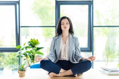 businesswoman meditating at workplace clipart