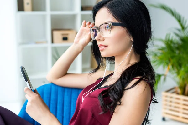 Femme d'affaires dans les écouteurs avec smartphone — Photo