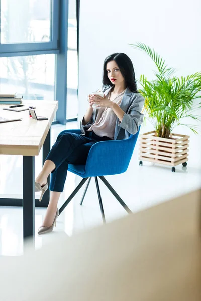 Zakenvrouw met kop koffie op werkplek — Gratis stockfoto