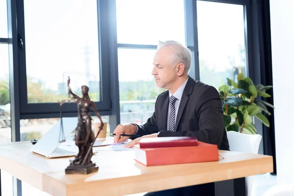 Mature lawyer sitting at workplace — Stock Photo, Image