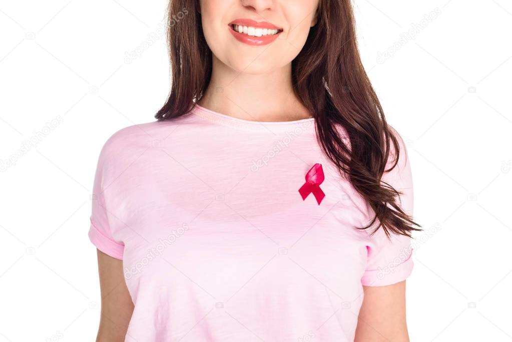 Cropped shot of young woman in pink t-shirt with breast cancer awareness ribbon smiling isolated on white