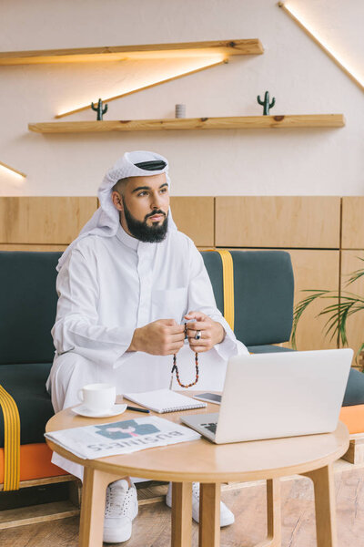 Мусульманский бизнесмен сидит на диване
