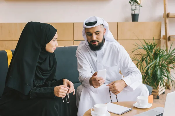 Muslim man showing smartphone to woman — Stock Photo, Image