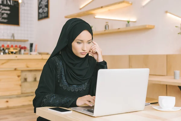 Muslim woman using laptop in cafe — Stock Photo, Image