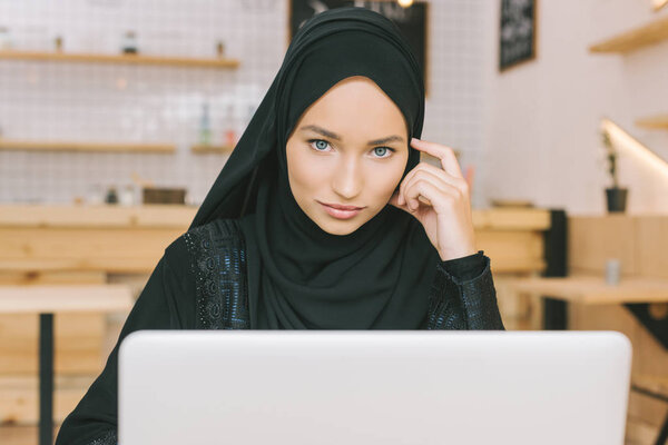 muslim woman using laptop in cafe