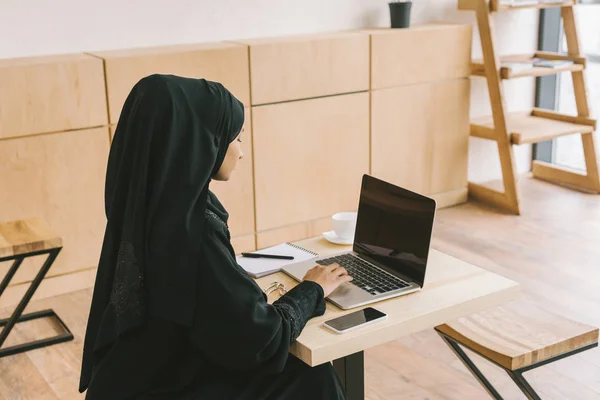 在咖啡馆里使用笔记本电脑的穆斯林女人 — 图库照片