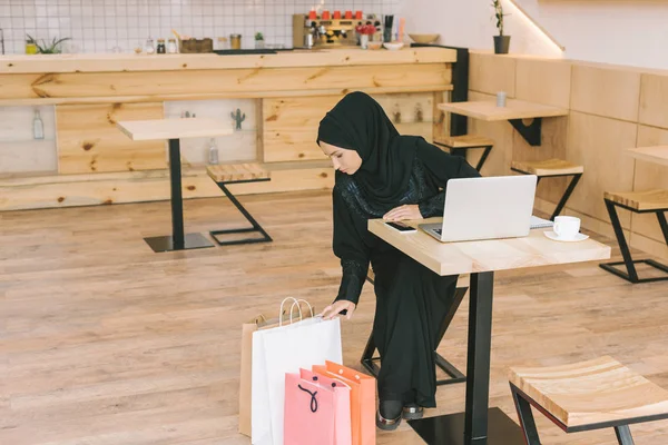 Mulher muçulmana olhando para sacos de compras — Fotografia de Stock Grátis