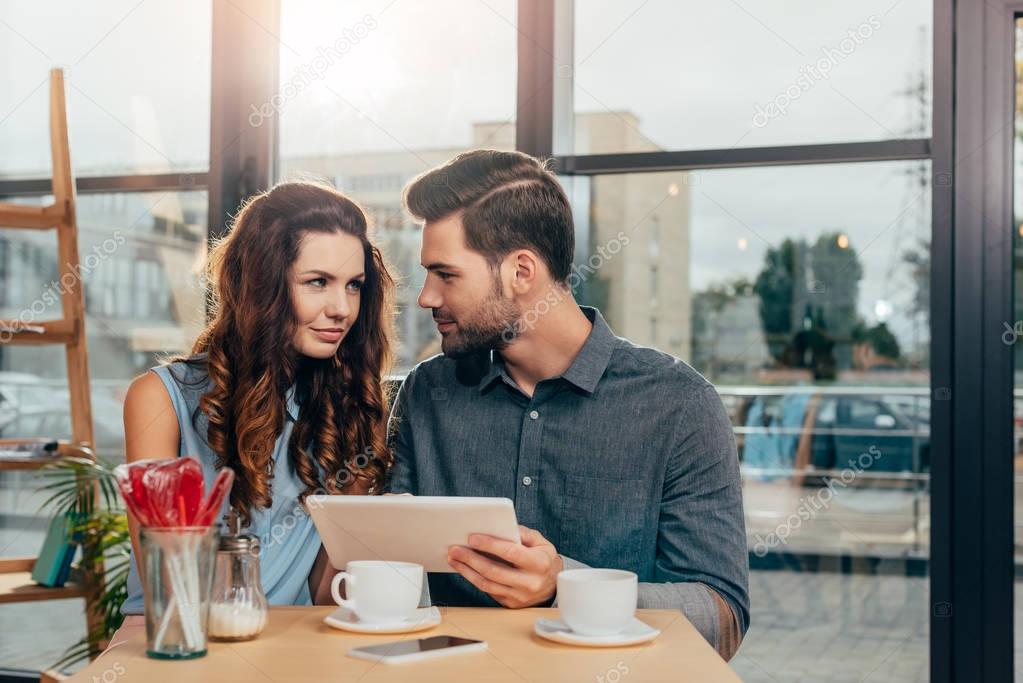 couple using tablet in cafe