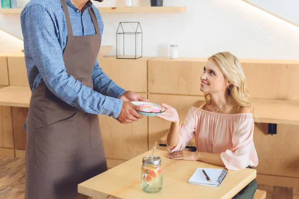 Waiter giving cookies to client — Stock Photo, Image