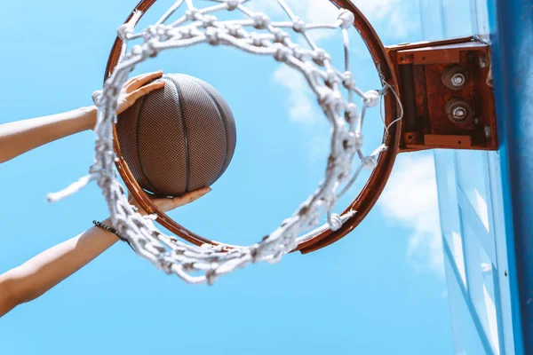 Hands throwing ball into basket — Stock Photo, Image