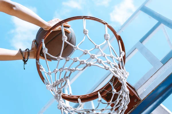 Hands throwing ball into basket — Stock Photo, Image