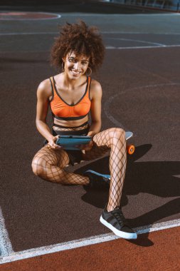 Afrikalı-Amerikalı kadın tablet ile longboard üzerinde