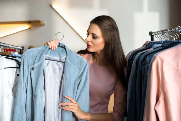 Молодая женщина выбирает одежду в бутике — стоковое фото
