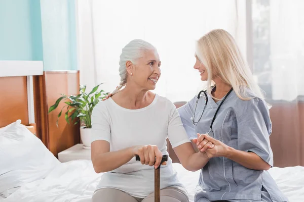 Verpleegkundige en senior vrouw met riet — Stockfoto