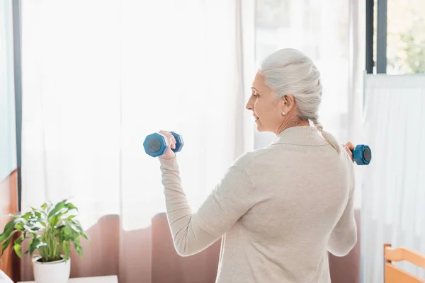 Senior woman with dumbbells in hospital — Stock Photo, Image