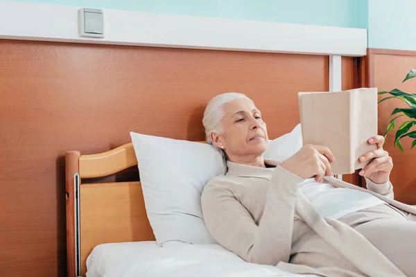 Mujer mayor con libro en el hospital — Foto de Stock