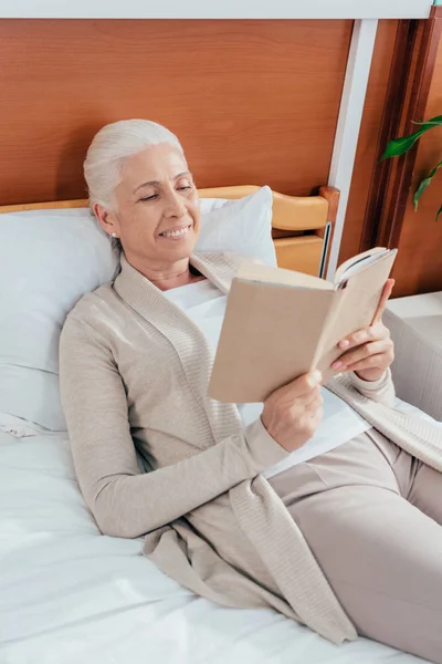 Mujer mayor con libro en el hospital — Foto de Stock
