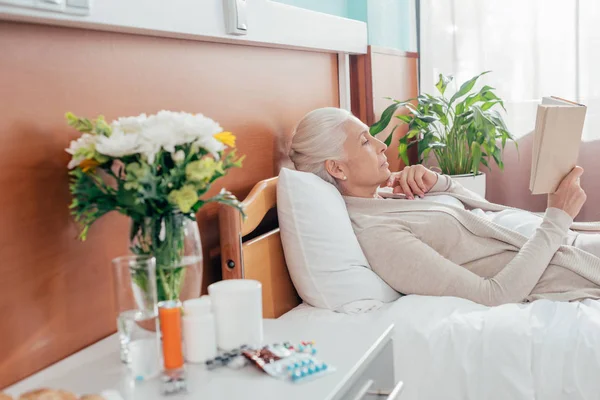 Senior vrouw met boek in ziekenhuis — Stockfoto