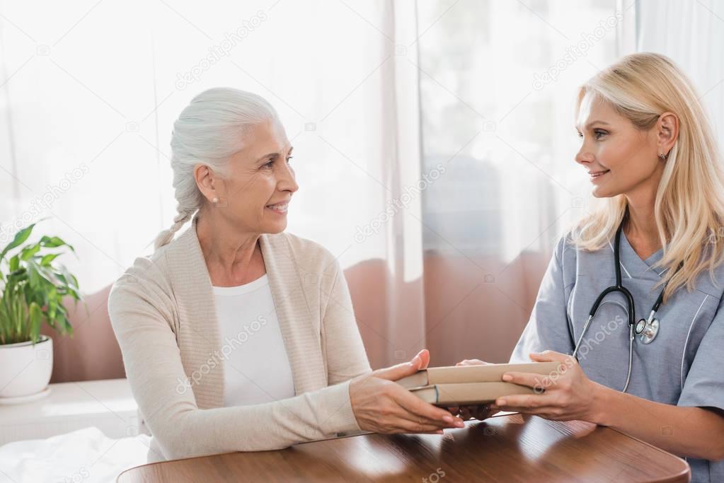 nurse and senior patient with books