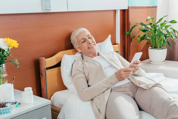 Senior woman with smartphone in hospital — Stock Photo, Image