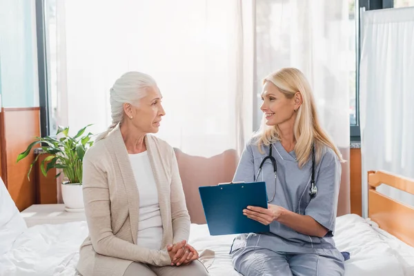 Senior woman and nurse with clipboard — Stock Photo, Image